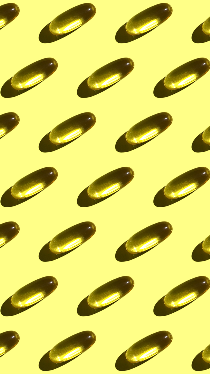 A vivid repetition of gelatin capsules creating a geometric pattern on a bright yellow background.