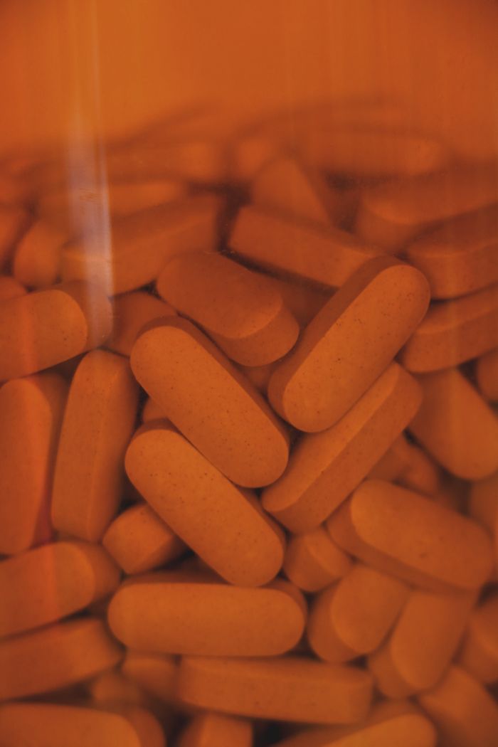 A vertical shot of orange pills in a glass container, representing healthcare and medication.